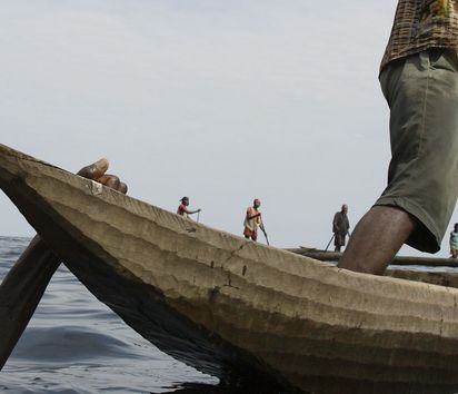 Fischer hält ein Boot fest während Netz aus Bambusstäben ausgelegt wird