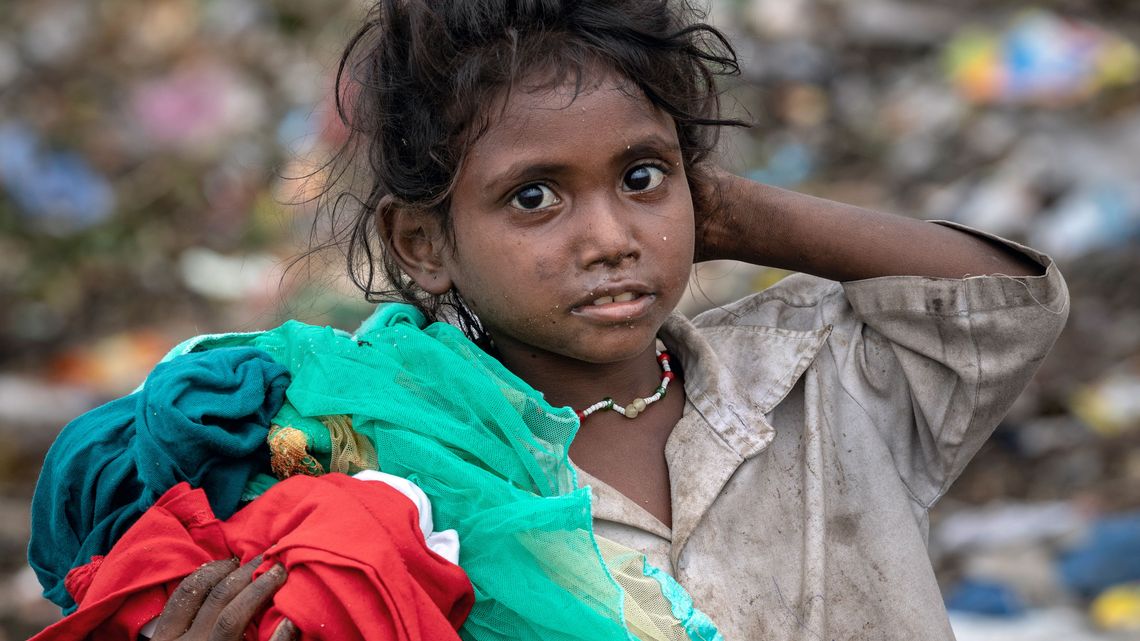 Ende 2018 besuchten die Autorin Nicole Graaf und der Fotograf Christoph Püschner zwei Wochen lang Müllsammler in Guntur, Indien. Im Auftrag der Hilfsorganisation Brot für die Welt, die in der Stadt Guntur die lokale Organisation DBRC (Dalit Bahujan Resource Center) zur Verbesserung der Lebensbedingungen der Müllsammler unterstützt, berichten die Reporter über den Alltag der dort lebenden Menschen. Die Bilder werden in der Ausstellung "Überleben im Müll" vom 12.06.-30.08.2020 im Willy-Brandt-Haus in Berlin gezeigt.Während die Eltern auf der riesigen Mülldeponie als Müllsammler arbeiten, hat das Mädchen inmitten der Müllberge abgetragene Kleidungsstücke gefunden.