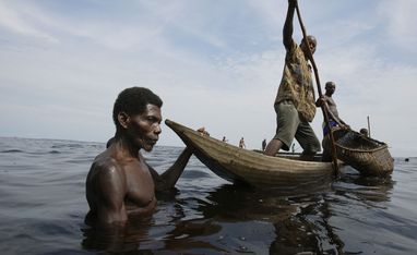 Fischer hält ein Boot fest während Netz aus Bambusstäben ausgelegt wird